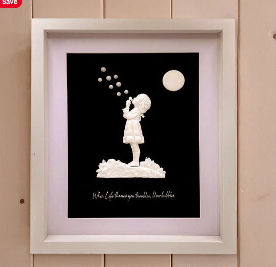 Framed artwork of a girl blowing bubbles with a moon in the background.
