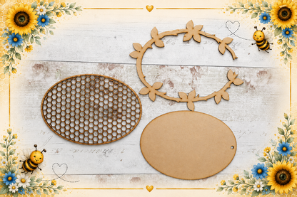 Three laser-cut wooden craft embellishments for scrapbooking or card making: an oval honeycomb-patterned piece, a blank oval card stock holder, and a floral vine frame. The items are arranged on a rustic white wood background decorated with sunflowers, bees, and hearts.